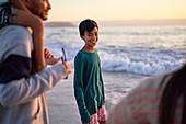 Portrait happy boy on ocean beach with family