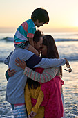 Affectionate family hugging on ocean beach