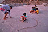 Family drawing in sand on beach
