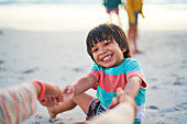 Happy boy holding hands with mother on beach