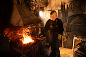 Female blacksmith working at foundry flame
