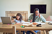 Mother paying bills next to daughter homeschooling