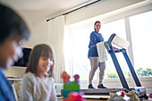 Mother exercising on treadmill and watching kids