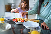 Mother and daughter eating fruit in kitchen