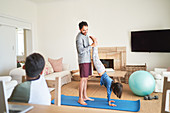 Father helping daughter to handstand on yoga mat