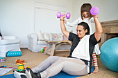 Daughter helping mother exercising with dumbbells