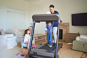 Mother and son walking on treadmill in living room