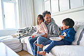 Father and kids eating popcorn on living room sofa