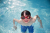 Portrait boy in goggles swimming