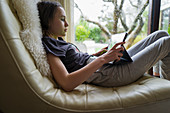 Girl using digital tablet in leather chair
