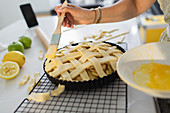 Close up woman brushing lattice pie with egg yolk