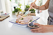 Woman brushing raw chicken with sauce