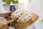 Woman slicing fresh homemade baked lattice pie