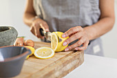 Close up woman slicing lemon on cutting board