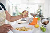 Woman squeezing lemon over sliced apples in bowl