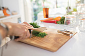 Woman cutting fresh dill on cutting board