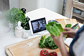 Woman cooking and video chatting with friends