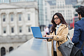 Business people using laptop on city bridge