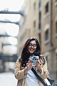 Smiling woman using smart phone on sidewalk