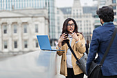 Business people with laptop talking on city bridge