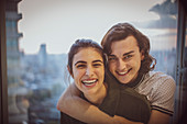 Portrait happy young couple hugging at window