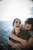 Happy young couple laughing and hugging on balcony