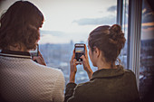 Couple photographing sunset at highrise window