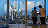 Businessmen at highrise office window, London, UK