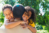 Happy daughter and son hugging father in park