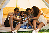 Happy family using smart phone inside tent
