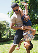 Playful father holding son upside down