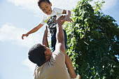 Father throwing son playfully overhead in sunshine