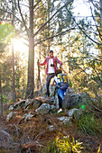 Young couple hiking up slope in sunny woods