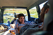 Couple relaxing and camping inside back of car