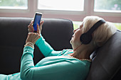 Senior woman relaxing and smart phone on sofa