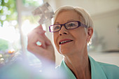 Curious senior woman examining cube in sunlight