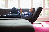 Senior man relaxing with tablet on sofa