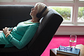 Senior woman listening to music on sofa