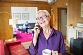 Senior woman with coffee talking on smart phone