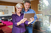 Happy senior couple using tablet in living room