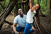 Father and daughter playing at tree in woods