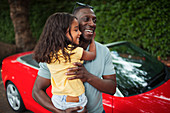 Happy father holding daughter outside convertible