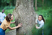 Playful mother and daughter at tree in woods