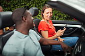 Couple using smart phone in convertible