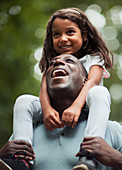 Happy father carrying daughter on shoulders