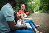 Happy family sitting on bench on path in park