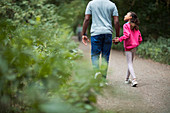 Father and daughter holding hands hiking on path