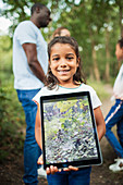 Portrait girl holding tablet with photo of plants