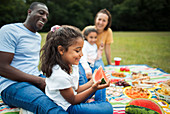 Happy girl eating watermelon with family