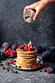 Ein Stapel Pancakes mit Himbeeren, Feigen, Blaubeeren und Ahornsirup